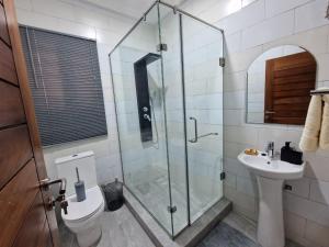 a bathroom with a shower and a toilet and a sink at Kirpal Villa in Kwabenya +16 photos