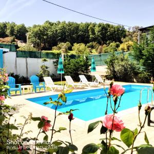 a swimming pool in a backyard with chairs and flowers at Villaferhat mavi in Karacaköy