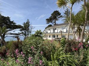 a white house with palm trees and flowers at Sunrise Bay - Mount Brioni in Downderry