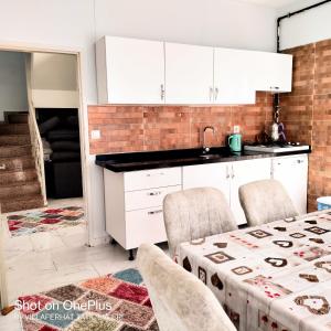 a kitchen with white cabinets and a table with chairs at Villaferhat mavi in Karacaköy