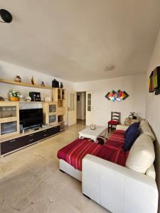 a living room with a white couch and a television at Bienvenido a tu habitacion in Málaga