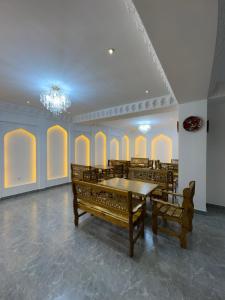 Un comedor con una mesa y bancos y una lámpara de araña. en Mashkobi Buxoro, en Bukhara