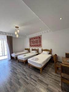 Habitación con 3 camas y mesa. en Mashkobi Buxoro, en Bukhara