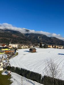 un grand champ enneigé avec une ville et des montagnes dans l'établissement Apartement Lampi, à Kötschach-Mauthen