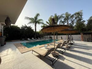 a group of chairs and umbrellas next to a pool at Villa Jude Luxury 6BR Villa with Private Pool, Sleeps 12, Near Golf & City in Marrakesh