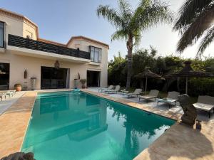 a swimming pool in front of a house at Villa Jude Luxury 6BR Villa with Private Pool, Sleeps 12, Near Golf & City in Marrakesh