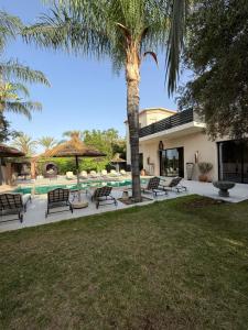 a house with a palm tree and a swimming pool at Villa Jude Luxury 6BR Villa with Private Pool, Sleeps 12, Near Golf & City in Marrakesh