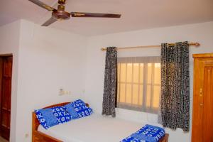 a bedroom with a bed with blue pillows and a ceiling fan at studio CHEZ VOUS in Lomé