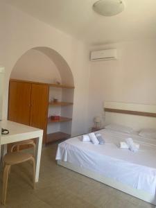 Un dormitorio con una cama blanca y un escritorio. en Castel Room, en Himare