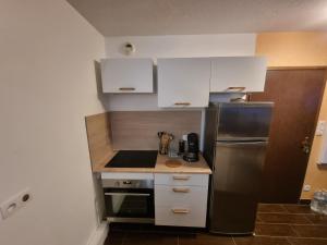 a small kitchen with white cabinets and a refrigerator at Duplex avec piscine et sauna in Jausiers