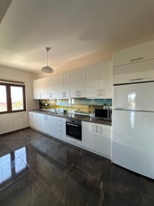 a large white kitchen with white cabinets and appliances at Natalie’s House in Alexandroupoli