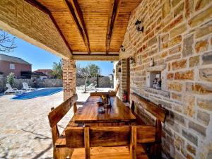 un patio con paredes de piedra, mesa de madera y bancos en Villa Bona, en Budak