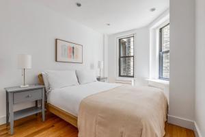 Un dormitorio blanco con una cama y dos ventanas. en Blueground Lincoln Sq gym wd nr park NYC-1849, en Nueva York