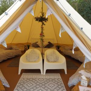 a tent with two chairs and a table in it at Hopgarden Glamping and camping - Luxury furnished Bell tents & Shepherd huts plus camp field to pitch your own tents in Wadhurst +155 photos