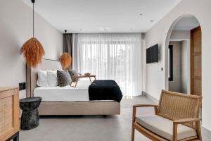a bedroom with a bed and a chair at Ammos Boutique Apartments & Suites in Malia