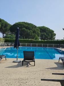 a blue swimming pool with a chair and an umbrella at Résidence Chiberta Anglet océan golf surf in Anglet