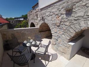 Un patio con mesa y sillas y un muro de piedra. en Vila Ema Dramalj, en Dramalj