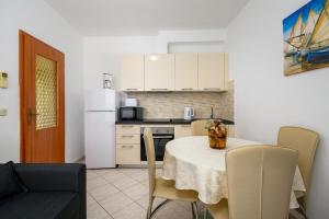 a kitchen with a table with chairs and a white refrigerator at Ferienwohnung 5235-2 in Drenje in Drenje