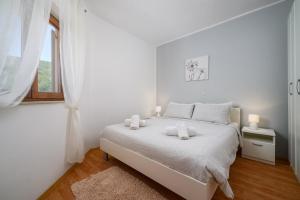 a white bedroom with a white bed and a window at Ferienwohnung 5235-2 in Drenje in Drenje