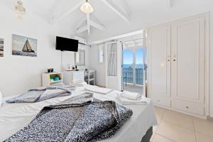 a white bedroom with a bed with a view of the ocean at Hotel Selini in Agios Nikitas