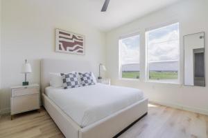 a white bedroom with a white bed and windows at Blueground Round Rock pool nr Old Settlers Park ATX-327 in Austin +23 photos