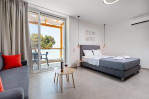 パレオコラにあるMeli apartments Paleochoraのベッドとソファと窓のある寝室