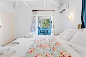 a white bedroom with a bed with a floral bedspread at Hotel Selini in Agios Nikitas