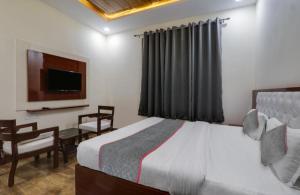 a bedroom with a bed and a desk and a television at RROOMS Trijal Hotel Banquet in Lucknow