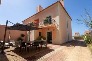 a patio with a table and chairs and an umbrella at Wave Song Villa in Santo Isidoro