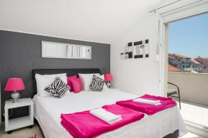 a bedroom with a large white bed with pink sheets at The Tribunj Suites in Tribunj