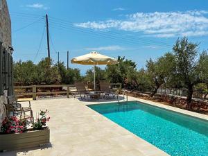 a swimming pool with an umbrella and a table and chairs at Mitso's House Mani in Exochori