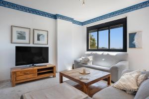 a living room with a couch and a tv at Apartamento Bahía Golf Suites in El Puerto de Santa María