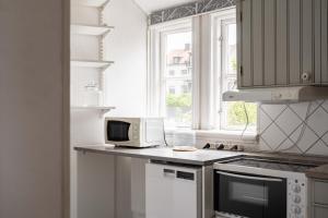 a white kitchen with a microwave and a window at Central located APT in heart of Visby in Visby