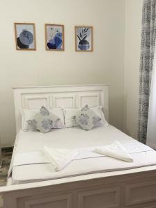 a white bed with four pictures on the wall at Aligna Bamburi in Mombasa