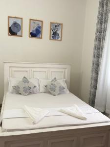 a white bed with four pictures on the wall at Aligna Bamburi in Mombasa