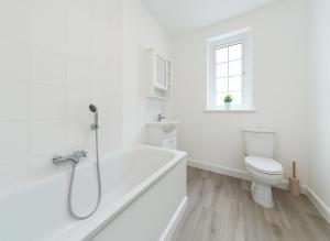 a white bathroom with a tub and a toilet at Spacious 2-Bedroom Apartment in Crystal Palace in London
