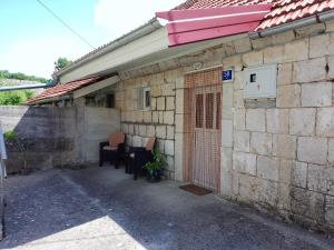a house with a table and chairs next to a building at Barun apartman in Lusnić