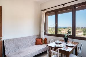 a living room with a table and a couch and windows at Selbesi Holiday Cottage in the countryside - Elevated View in Kómi +3 photos