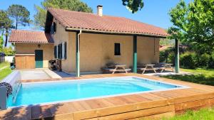 a pool with a wooden deck and a house at L'OREE DE LA PLAGE, 15 pers, Charmante Maison rénovée classée 3 étoiles - Piscine chauffée - Terrain de pétanque - Ping pong à Vieux-Boucau in Vieux-Boucau-les-Bains