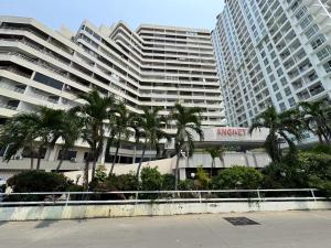 un grand bâtiment avec des palmiers devant dans l'établissement Angket Select Resort Pool Apartment, à Jomtien Beach