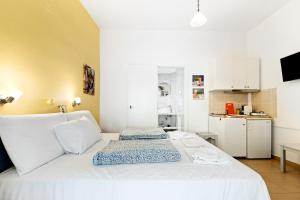 a white bed in a room with a kitchen at Hotel Selini in Agios Nikitas