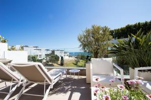 un patio con sillas blancas y vistas al océano en Front line Golf and tranquility, en Marbella