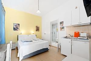 a bedroom with a white bed and a kitchen at Hotel Selini in Agios Nikitas