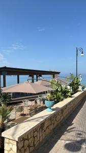 a stone wall with chairs and tables and umbrellas at Paguro Beach Hotel in Siculiana Marina