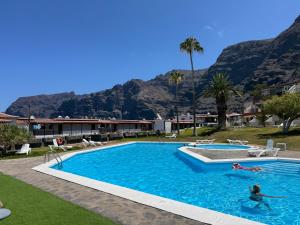 zwei Personen in einem Schwimmbad mit Bergen im Hintergrund in der Unterkunft Casa Oceanico Los Gigantes in Acantilado de los Gigantes