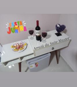 ein weißer Tisch mit zwei Gläsern Wein und einer Flasche in der Unterkunft Suíte Master in Frederico Westphalen + 4 Fotos