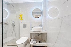 a white bathroom with a toilet and a shower at Hotel Selini in Agios Nikitas