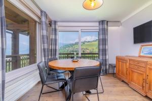 a dining room with a table and chairs and a large window at Chalet Nessa in Combloux