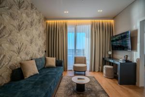 a living room with a couch and a table and a desk at Hotel Majestic in Durrës