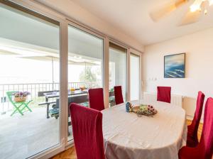 a dining room with a table with red chairs and a table with a view at Fia 70s Beach Apartment in Rab